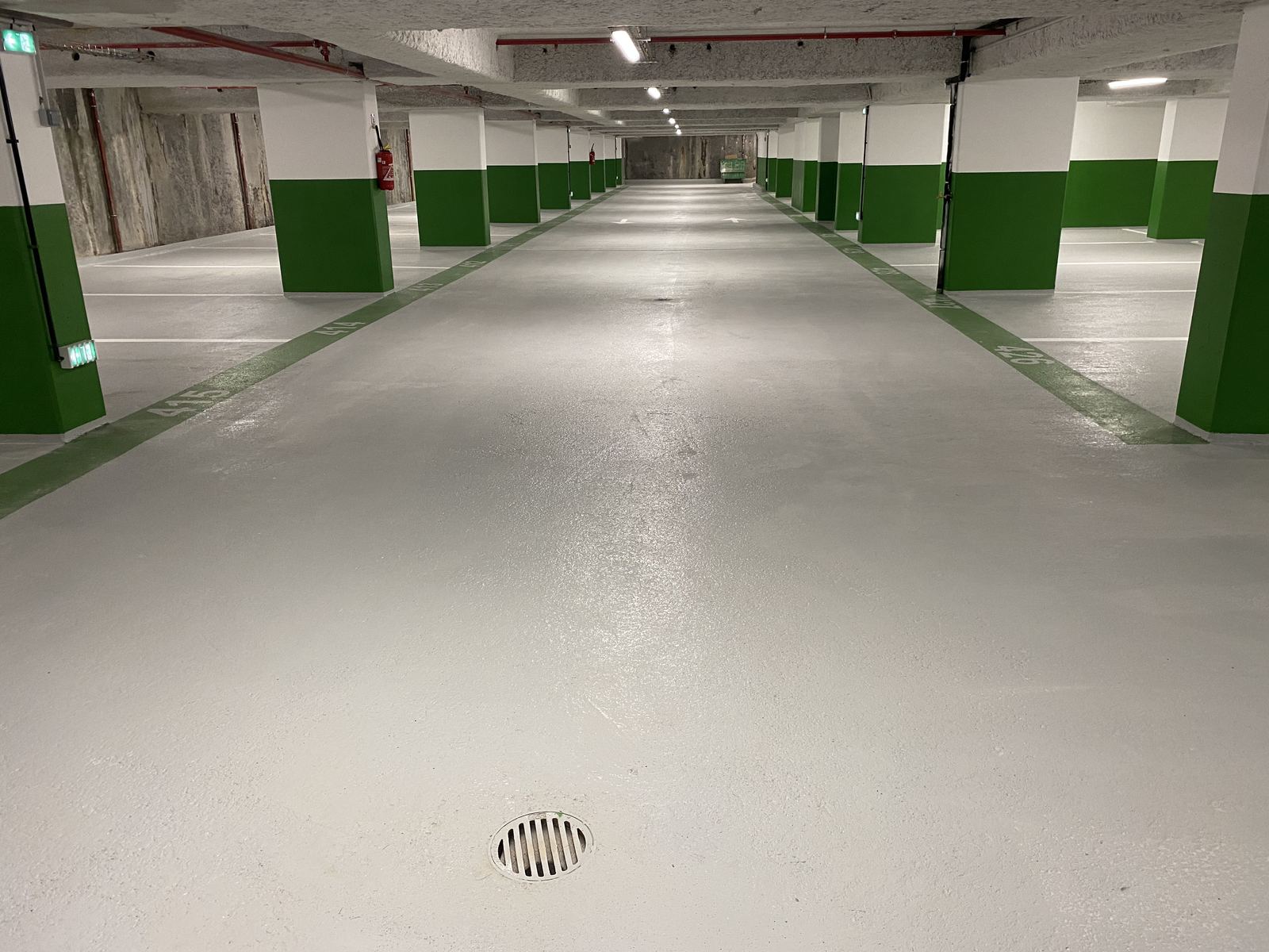 Parking rénové — poteaux verts et blancs, allée centrale